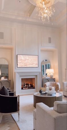 a living room filled with furniture and a fire place under a chandelier in front of a window