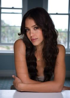 a woman sitting at a table with her arms crossed and looking off to the side