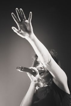 a woman with her hand up in the air while holding a microphone to her mouth