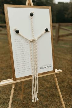 a sign with ropes attached to it on top of a wooden easel in the grass