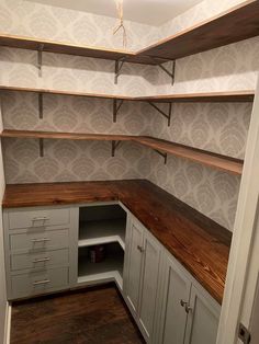 an empty walk in closet with wooden shelves