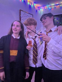 three people standing next to each other wearing harry potter shirts and ties with lights in the background