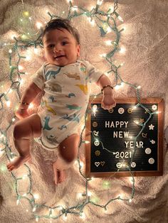 a baby laying on top of a blanket next to a sign that says happy new year