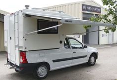 a small white truck with a camper attached to it's back end in front of a building