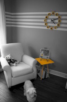 a white chair sitting in a living room next to a small table with a stuffed animal on it