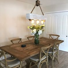 a wooden table with chairs around it and flowers in a vase at the end of the table