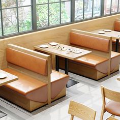 an empty restaurant with wooden booths and leather seats, along with plates on the table