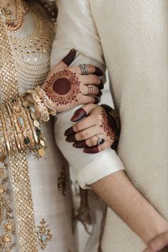 two brides holding hands with henna on their fingers and wearing matching bracelets