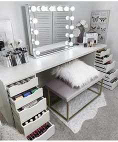 a white vanity with lights on it and drawers under the mirror in front of it