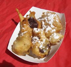 some food is sitting in a white box on a red tablecloth and it has powdered sugar on top