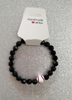 the black beaded bracelet has a red and white baseball charm on it's side