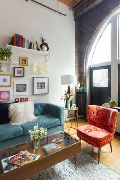 a living room filled with furniture next to a tall arched window and lots of windows