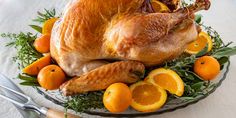 a roasted turkey on a platter with oranges and herbs