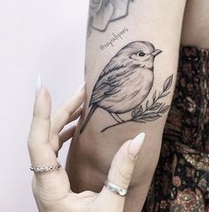 a woman's arm with a bird tattoo on it