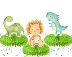 three paper dinosaurs sitting on top of green leaves with confetti scattered around them