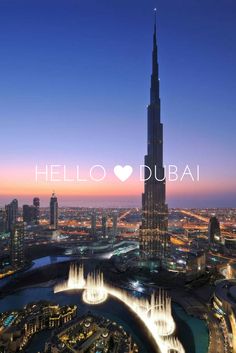 the burj tower towering over the city at night, with water fountains in front