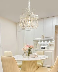 a dining room table with four chairs and a chandelier hanging from the ceiling