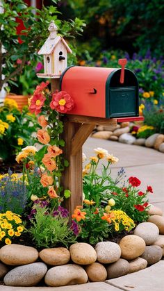 a mailbox is surrounded by flowers and rocks