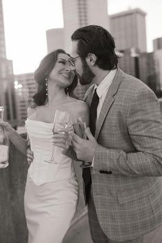 a man and woman standing next to each other holding wine glasses