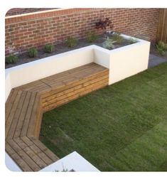 a wooden bench sitting on top of a lush green field next to a brick wall