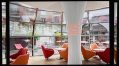 the interior of a restaurant with orange chairs and tables in front of large glass windows