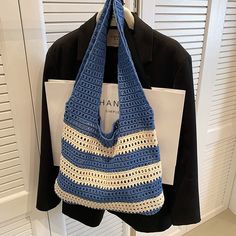 a blue and white crocheted bag hanging from a coat hanger on a door