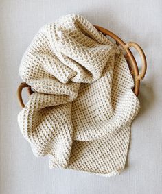 a white knitted blanket sitting on top of a wooden basket