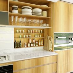 a kitchen with wooden cabinets and white marble counter tops, filled with jars and glasses