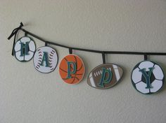 decorated cookies hanging from a line with letters and sports balls on the clothes pegs