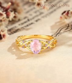 a pink stone ring sitting on top of a piece of paper next to some flowers