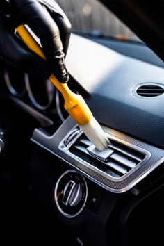 a person in black gloves is cleaning the interior of a car with a yellow brush