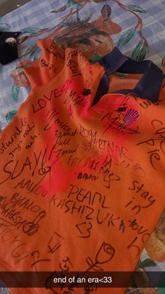 an orange blanket with writing on it sitting on top of a bed covered in sheets