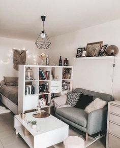 a living room filled with furniture next to a white table and bookshelf on top of a hard wood floor