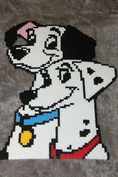 a beaded dalmatian dog sitting on top of a gray floor next to a rug