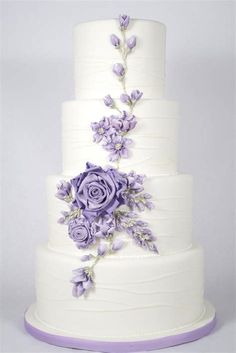 a three tiered cake with purple flowers on it