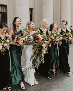 a group of women standing next to each other in front of a building holding bouquets