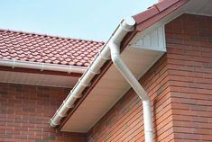 a red brick building with a white gutter hose attached to it's side