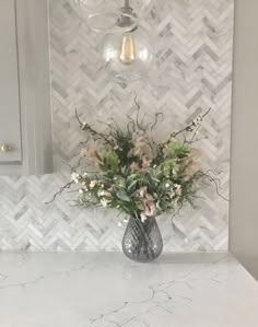 a vase filled with flowers sitting on top of a counter next to a light fixture