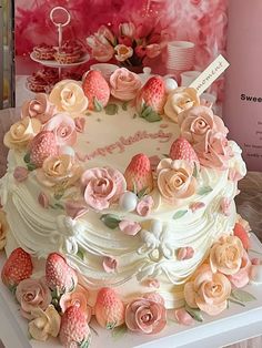 a white cake with pink and yellow flowers on it's side sitting on a table