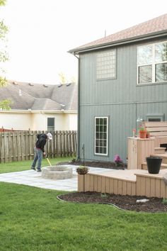 a man is shoveling the grass in front of a house with his back yard