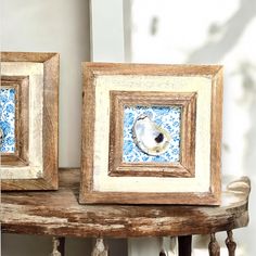 two wooden frames with blue and white designs on them, one has a seashell in it