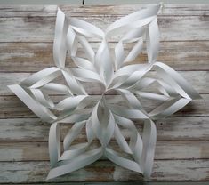 a white paper snowflake sitting on top of a wooden table