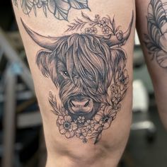 a woman's thigh with a tattoo of a bull and flowers on the side