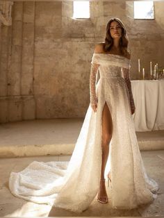 a woman in a white wedding dress standing next to a table with candles on it