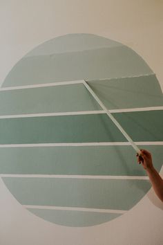 a person painting a wall with green and white stripes