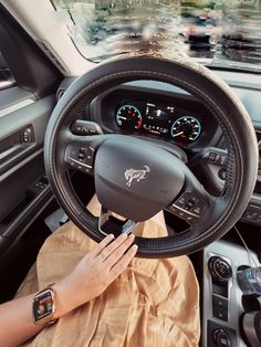 a woman is sitting in the driver's seat of a car with her hands on the steering wheel