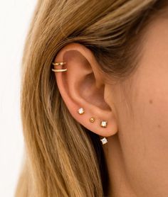 a close up of a woman's ear with three small diamond studs on it