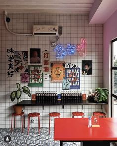 the interior of a restaurant with colorful neon signs on the wall and tables in front of it