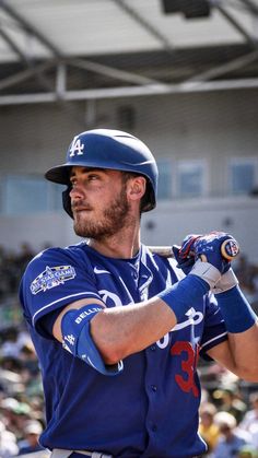 a baseball player holding a bat in front of a crowd at a ball park during the day