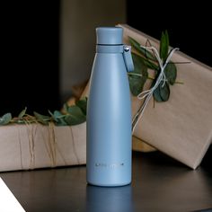 a blue water bottle sitting on top of a table next to a box and plant